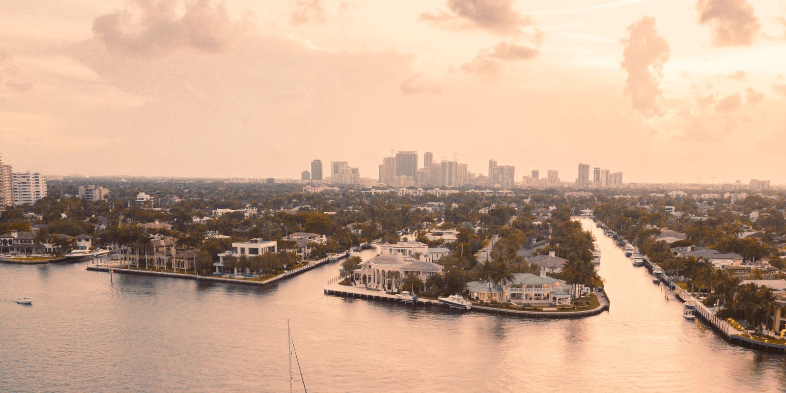 Barcos sobre el agua en calma al atardecer en Fort Lauderdale, con las torres del centro en el horizonte.