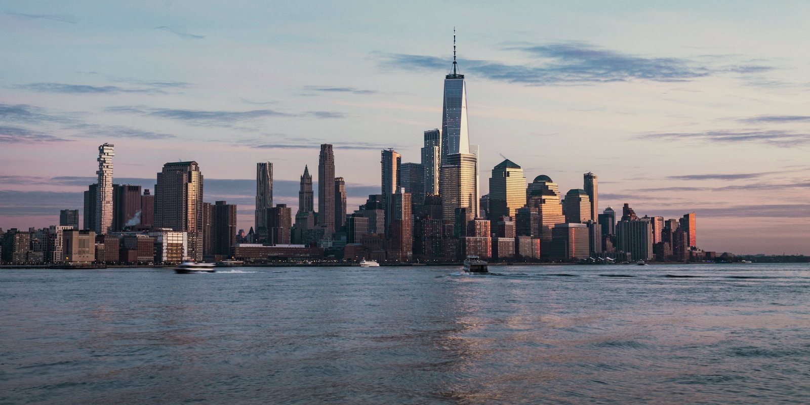 Lower Manhattan seen across the Hudson River in low evening light.