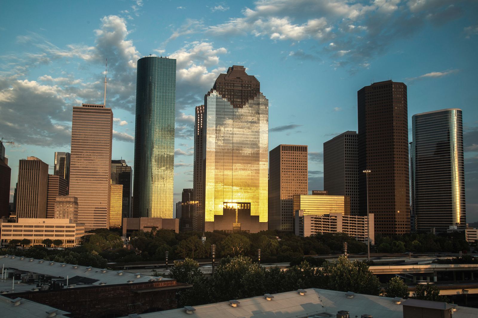 Downtown Houston towers in late sun, one gold tower reflecting the light.