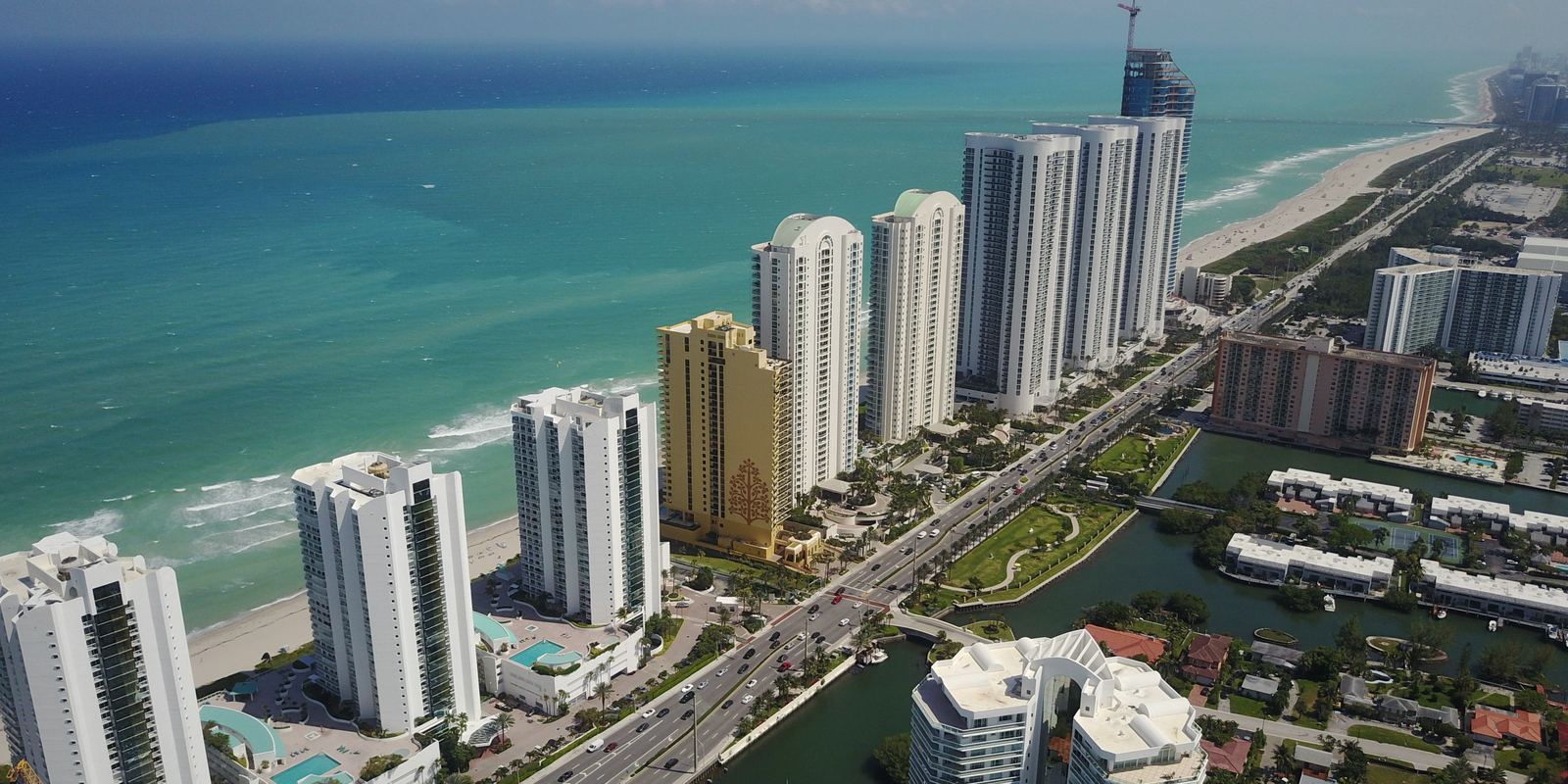 Sunny Isles Beach desde el aire: una fila de torres altas entre el Atlántico y los canales del lado de la bahía.